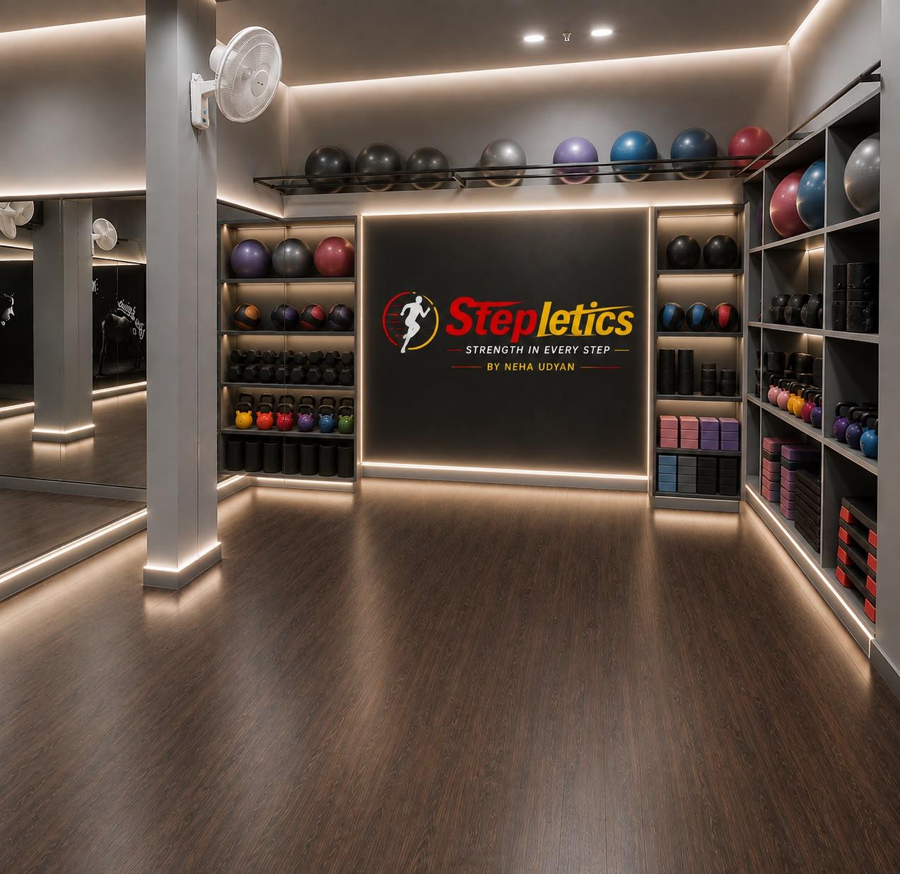 Shelves of medicine balls, kettlebells and dumbbells beside the backlit Stepletics logo panel